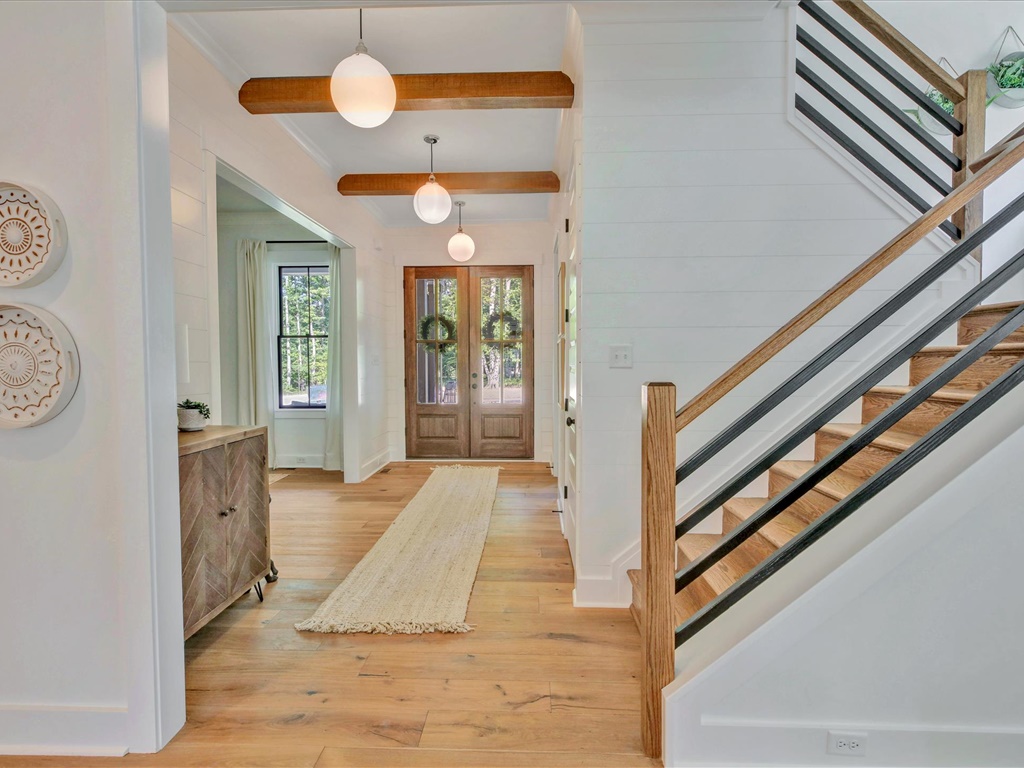 Foyer with beamed ceiling, double doors, and open staircase