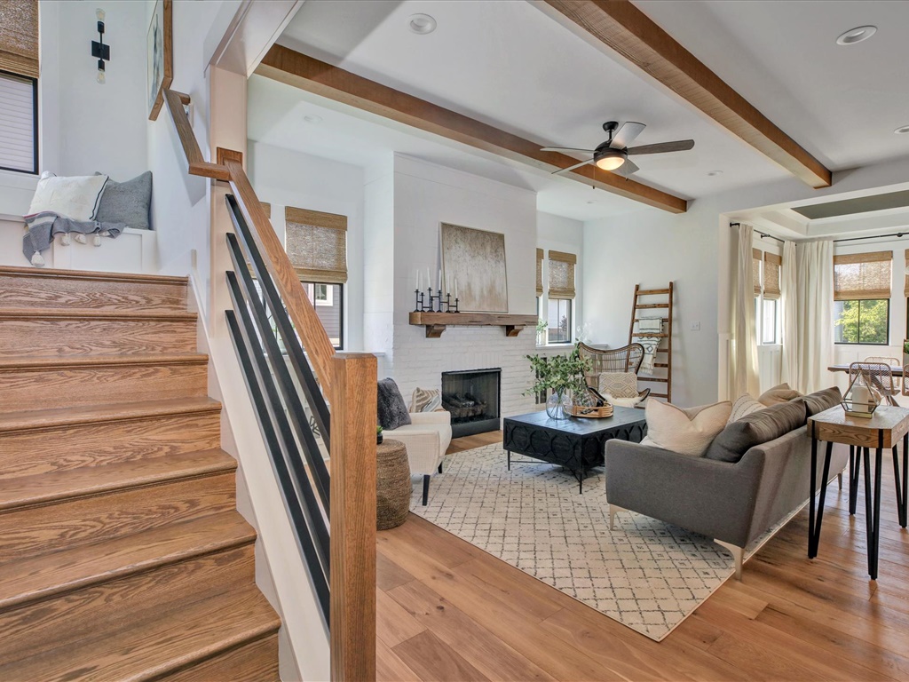 Living room with wood beams, fireplace, and open staircase