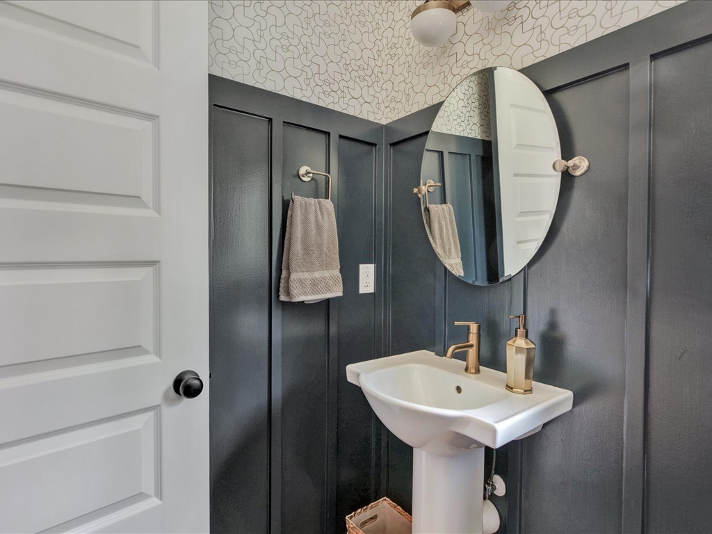 Powder room with navy board-and-batten and patterned wallpaper